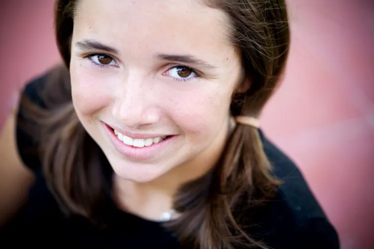 Portrait of a young girl with brown hair in pigtails, smiling happily.