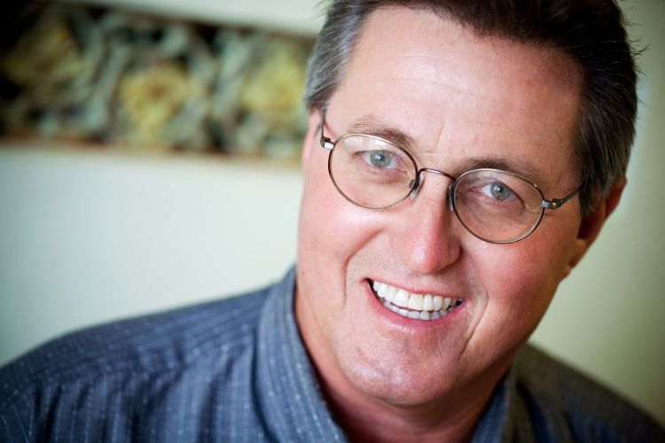 A middle-aged man with glasses and short hair, looking into the camera with a relaxed smile.
